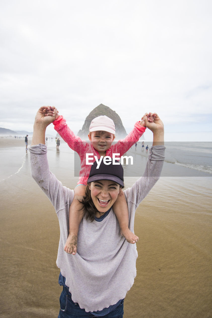 Happy mom gives daughter shoulder ride at cannon beach.