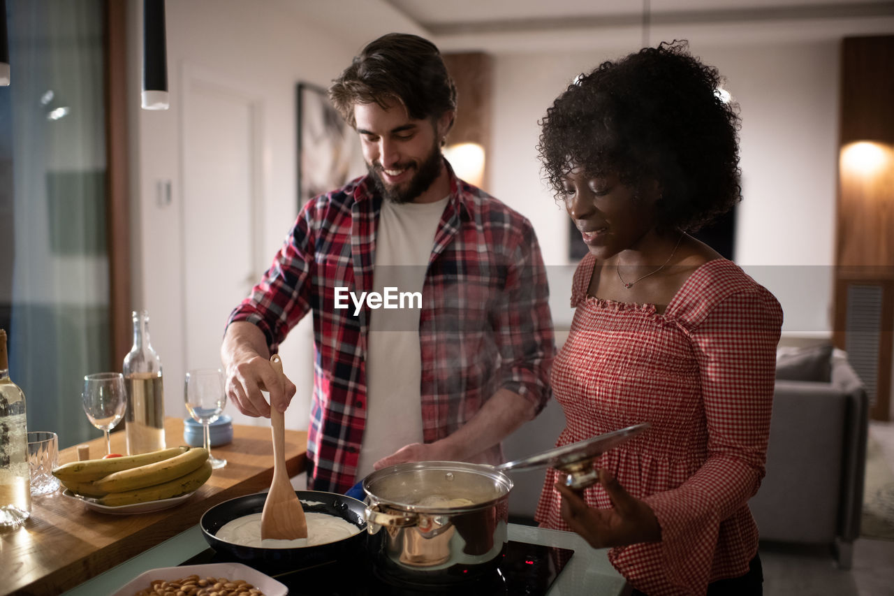 Diverse couple preparing romantic dinner in kitchen