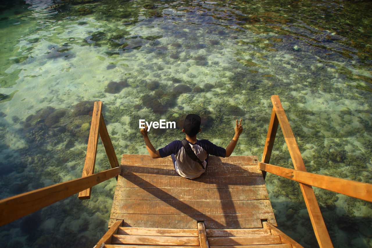 High angle view of man sitting on jetty