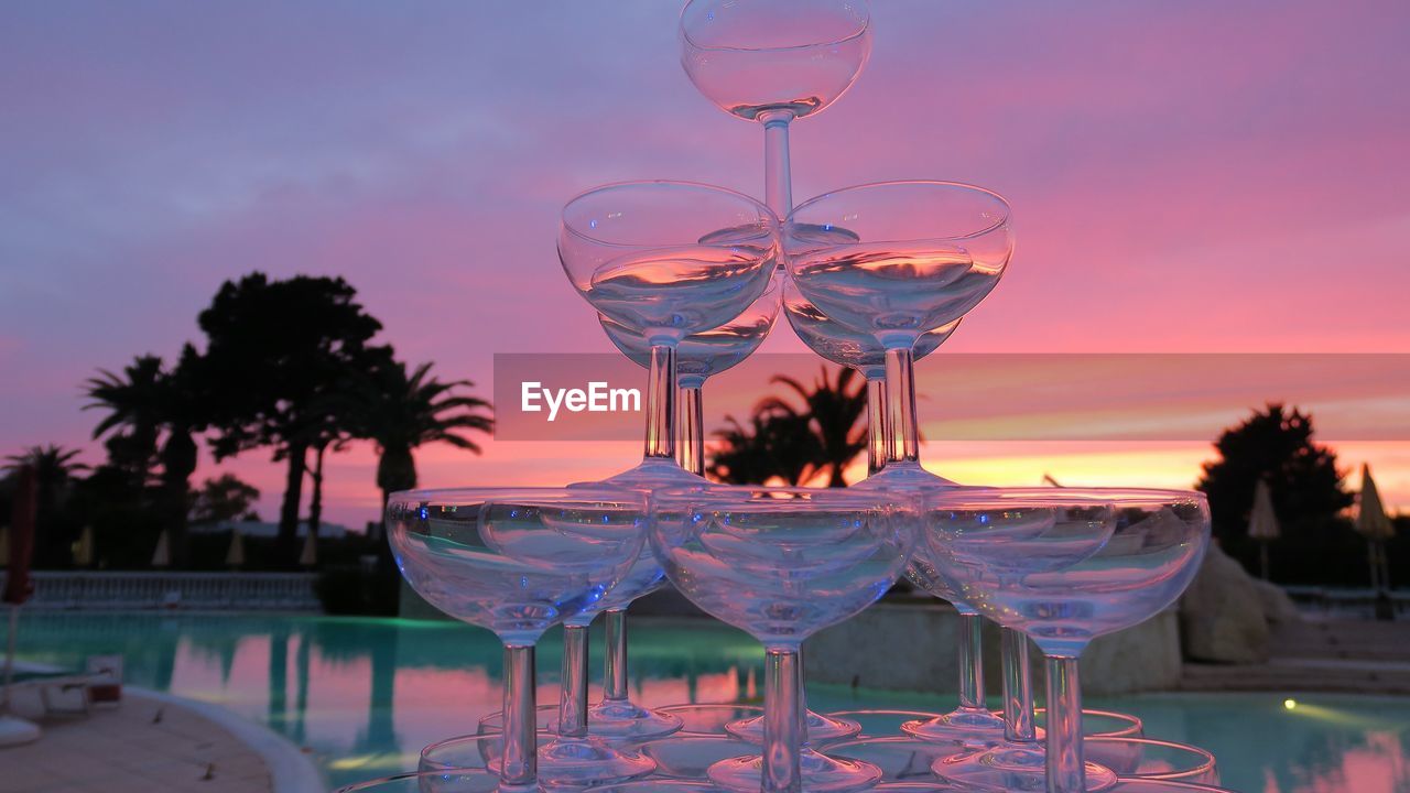 Stack of martini glass on table against sky during sunset