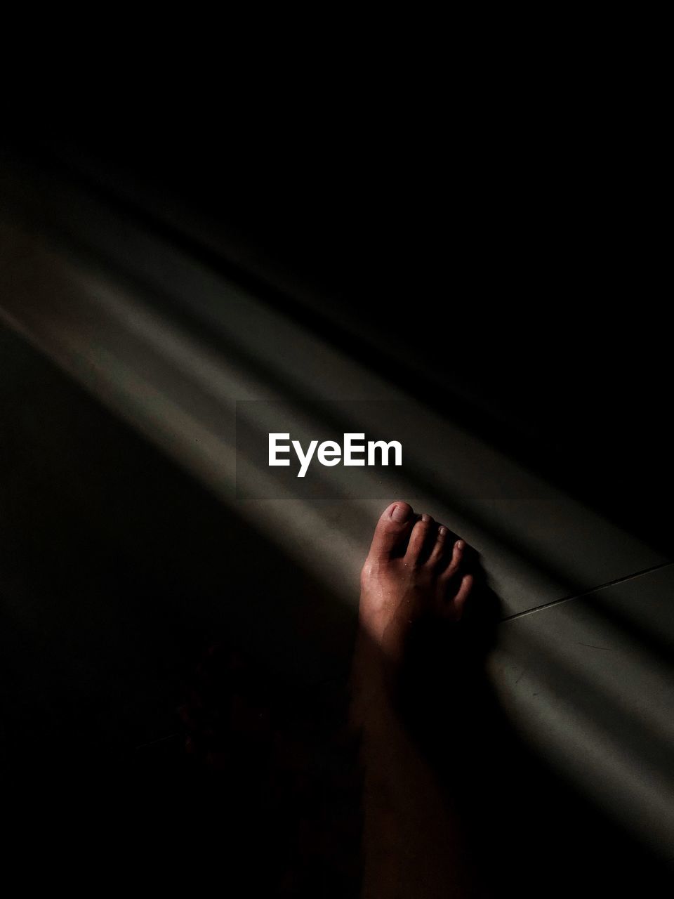 Low section of person on tiled floor in darkroom