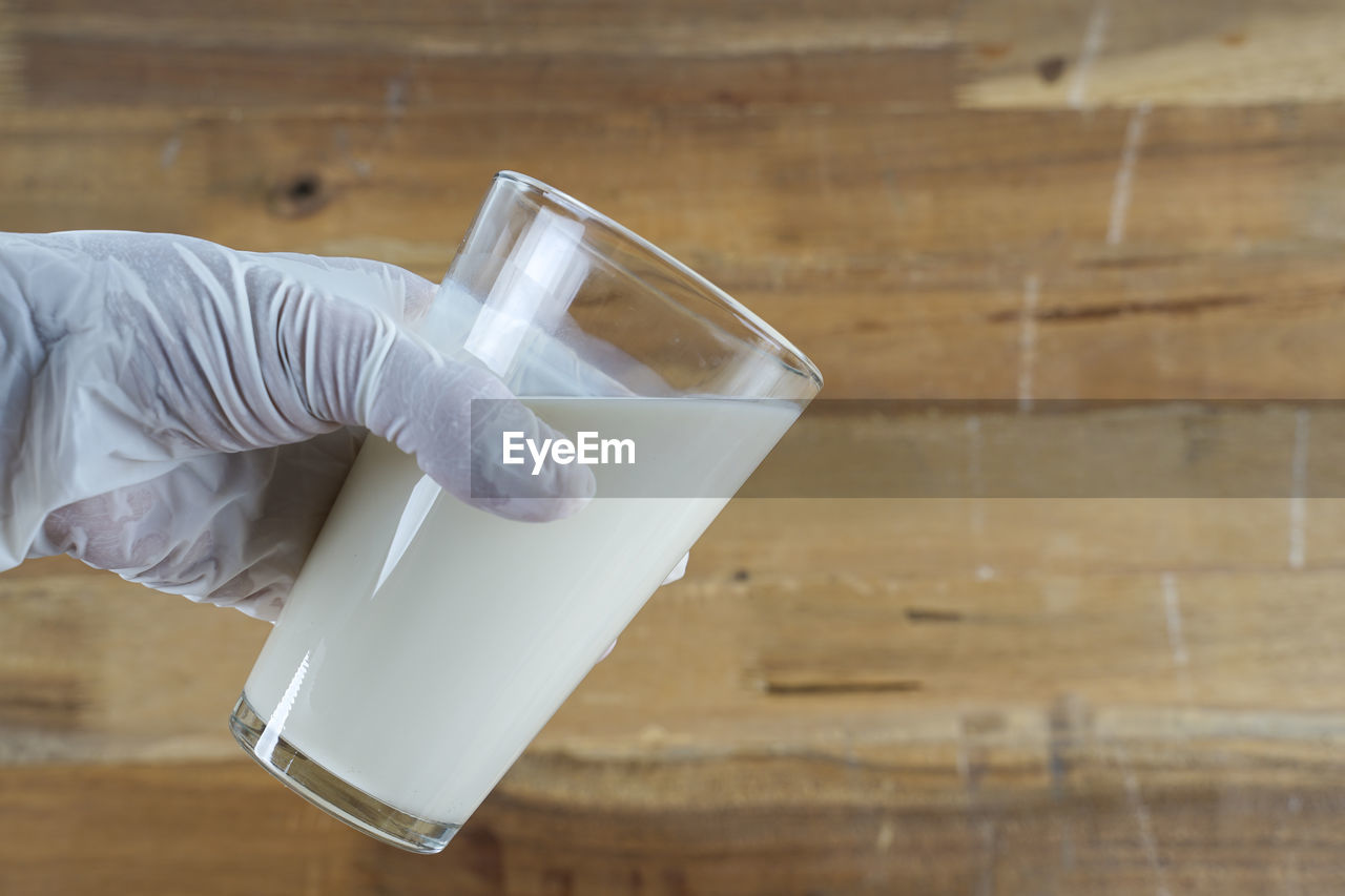 CLOSE-UP OF HAND HOLDING GLASS OF WATER