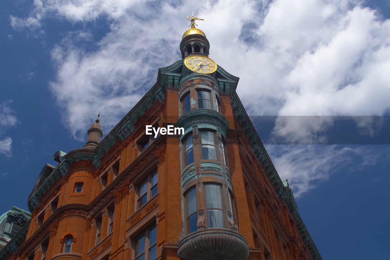 LOW ANGLE VIEW OF CLOCK TOWER AMIDST BUILDING AGAINST SKY