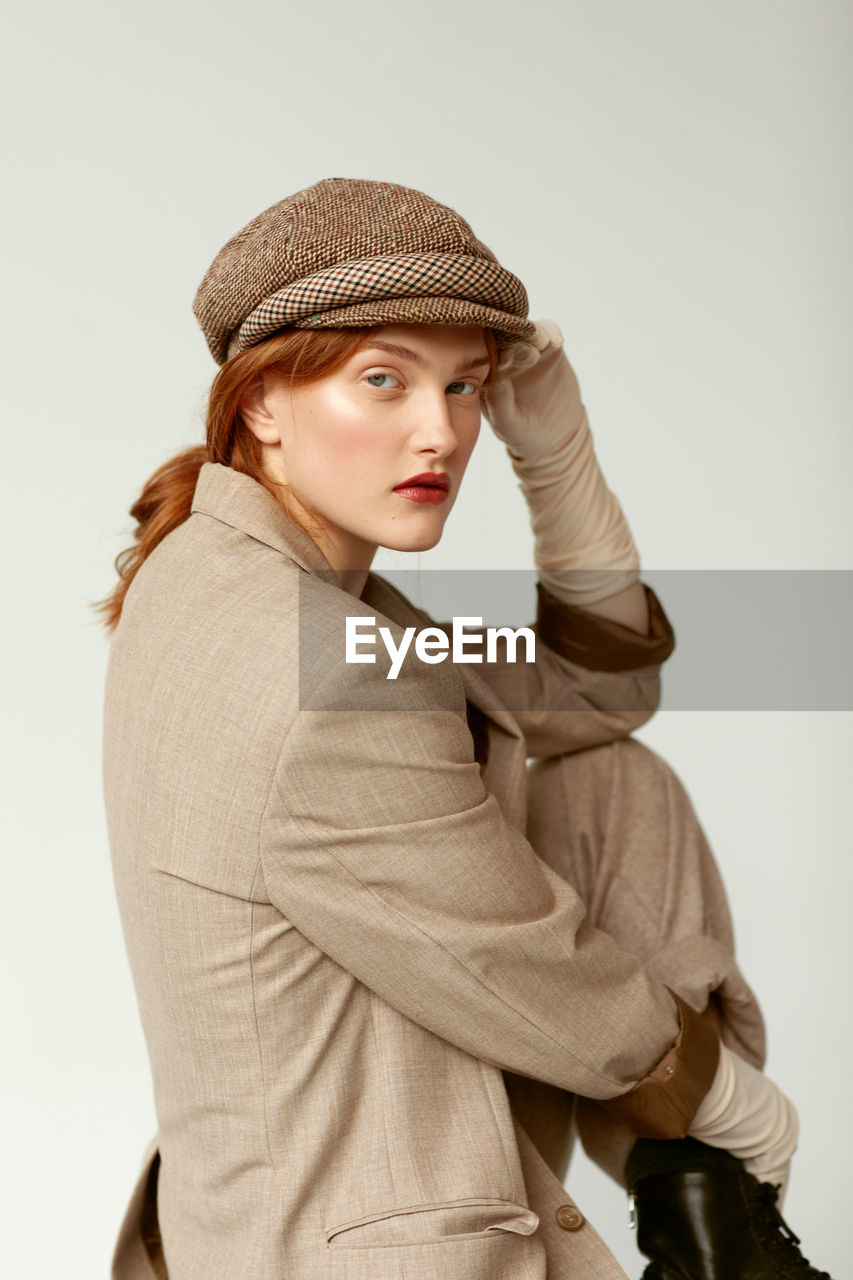 Portrait of young woman wearing hat against white background