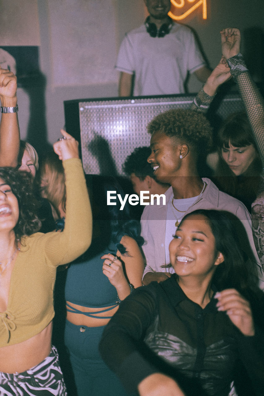 Cheerful young multiracial men and women dancing at nightclub