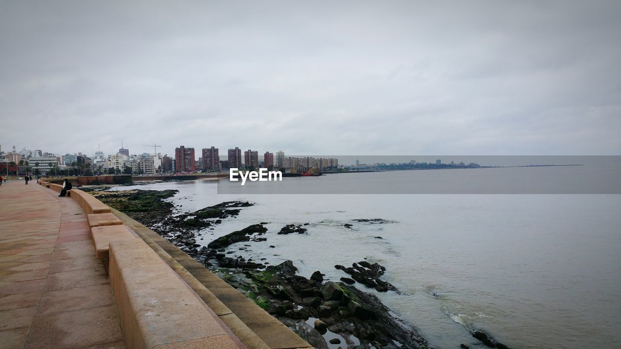 Sea by city against sky
