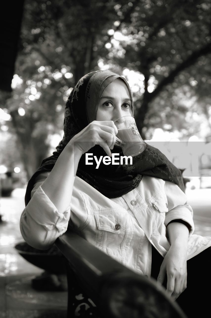 Young woman having drink while sitting on chair