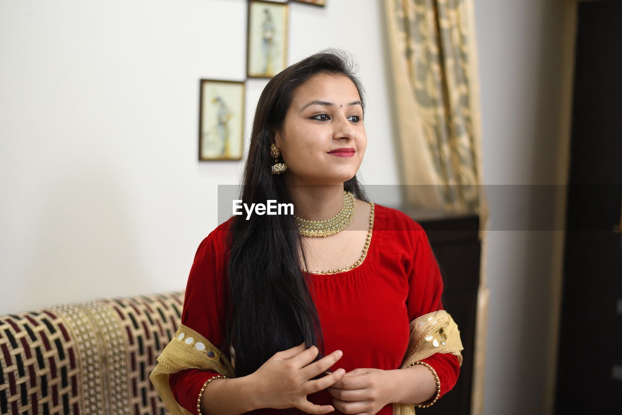 Smiling woman in traditional clothing standing at home