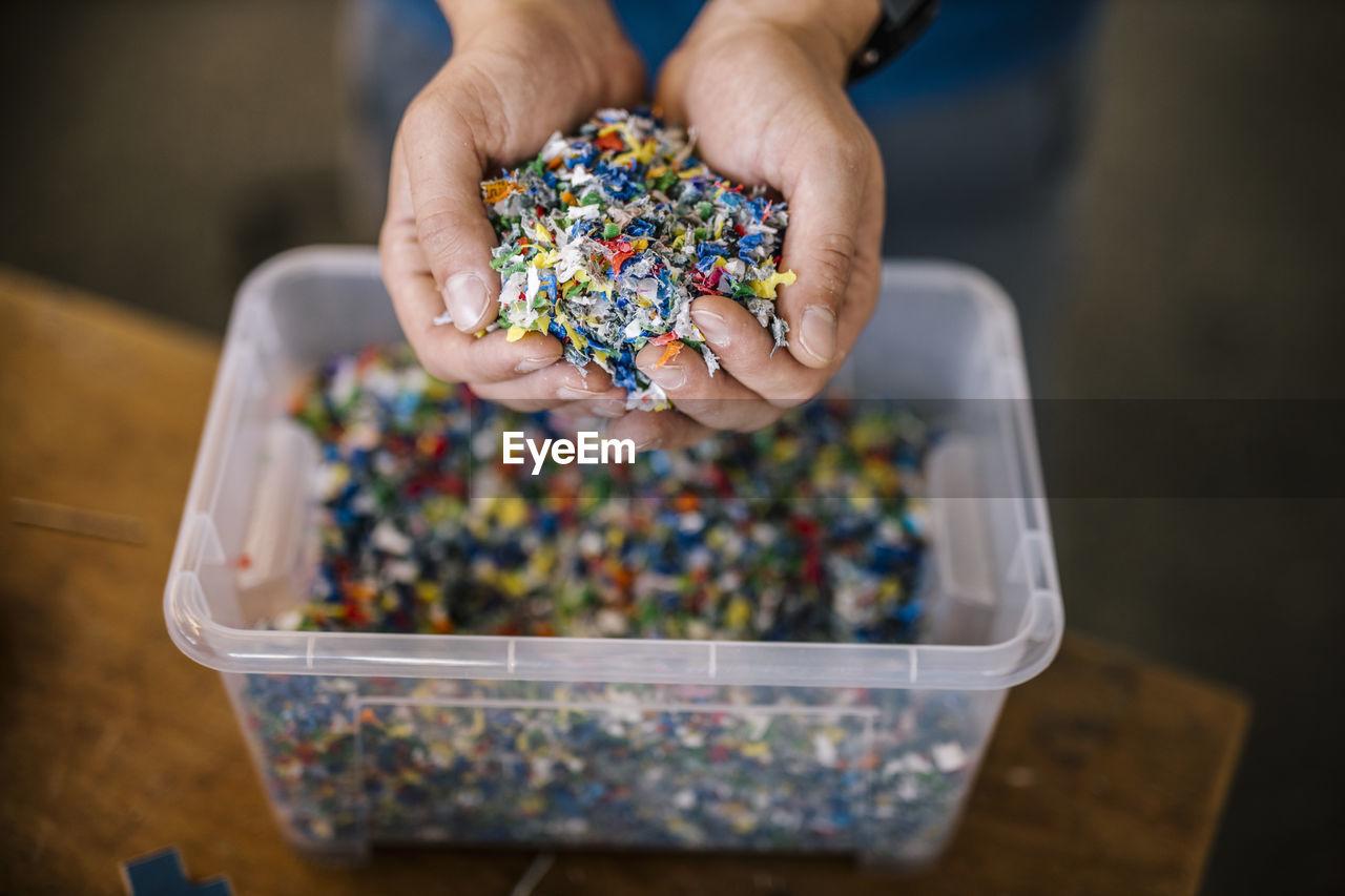 Man with container holding recycled plastic in factory