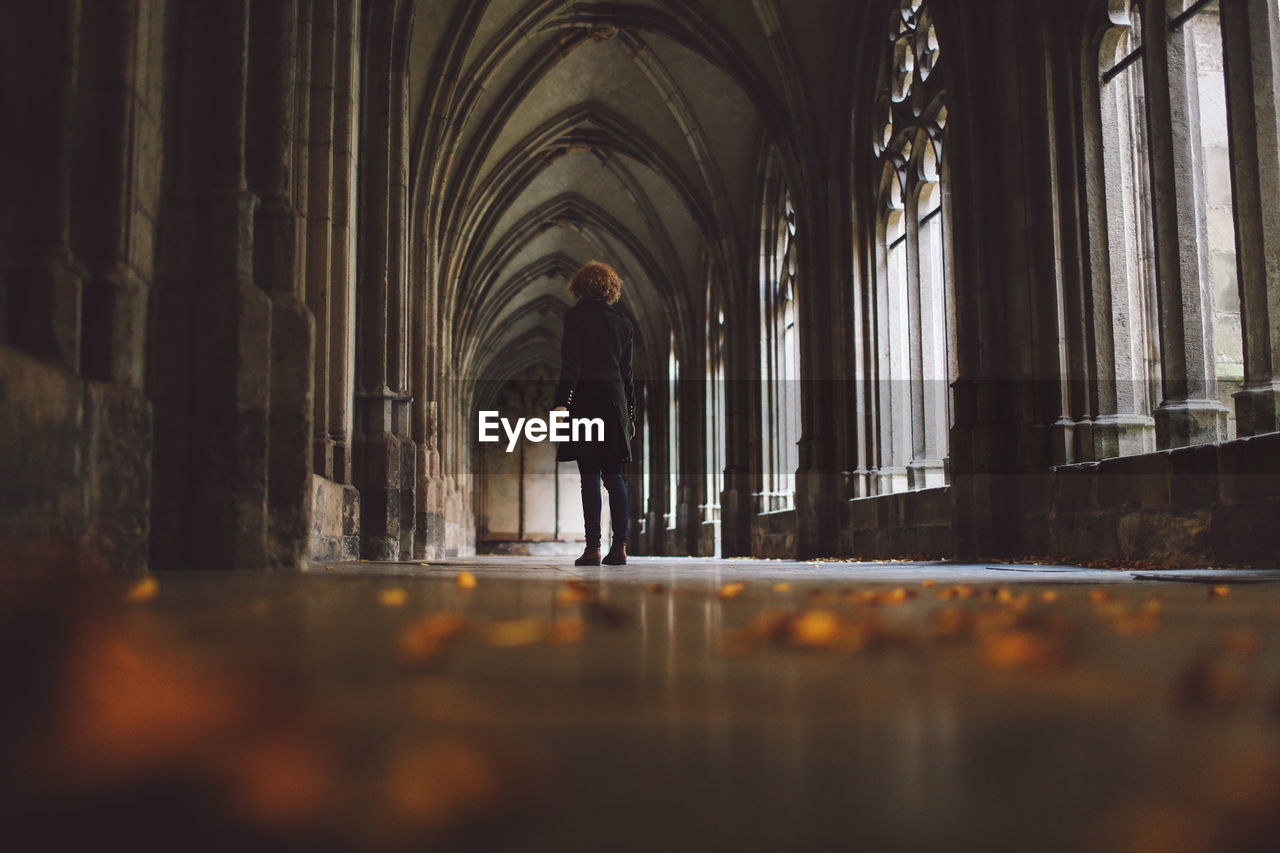 Low angle view of young woman standing at church corridor