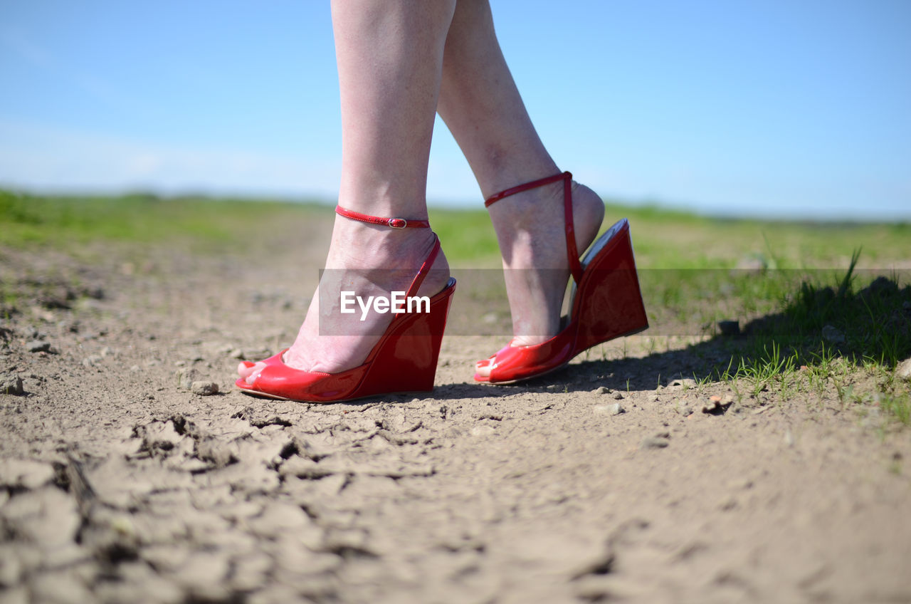 Low section of woman wearing red high heels on land