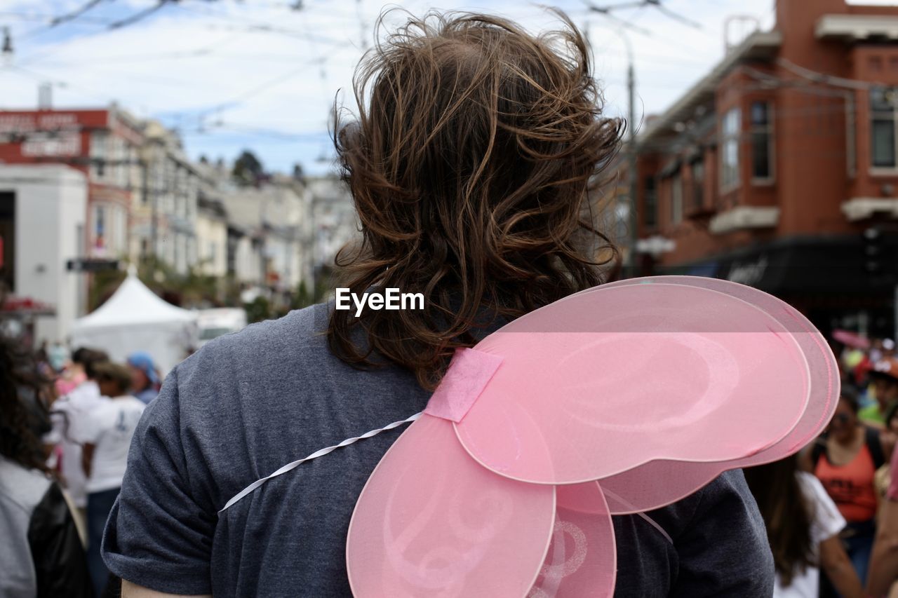 REAR VIEW OF WOMAN STANDING AGAINST CITY