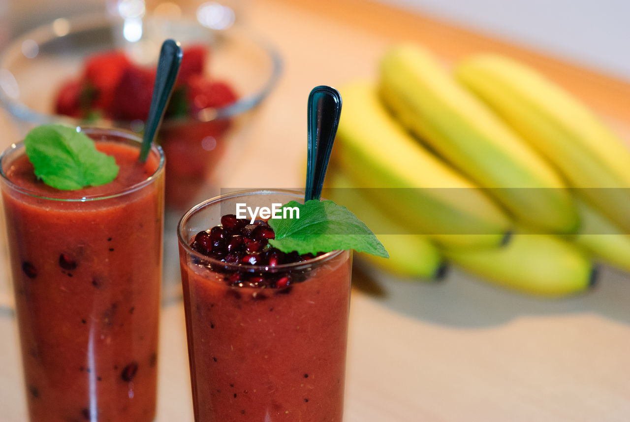 Close-up of juices by bananas on table