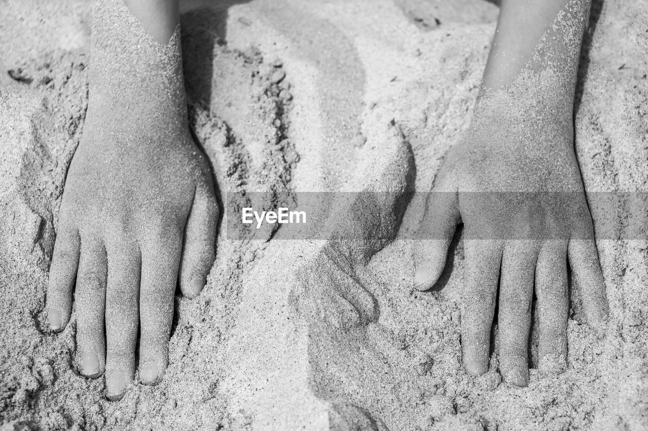 Cropped hands of child on sand at beach