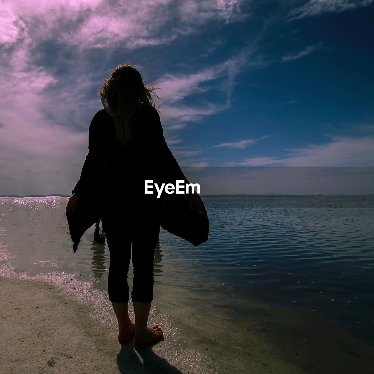 Person standing on beach at sunset