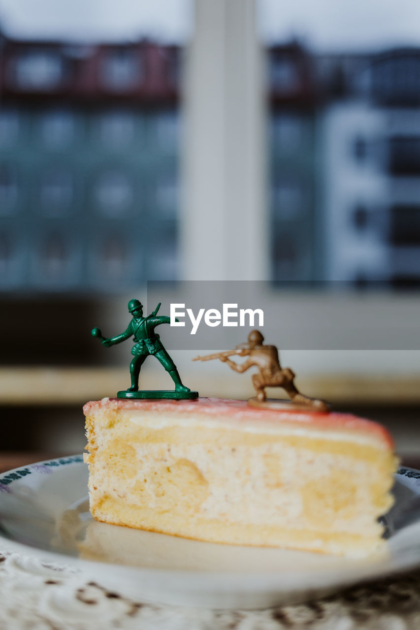 Two toy soldiers fighting on the top of a piece of cake about having a dessert or not - close up 