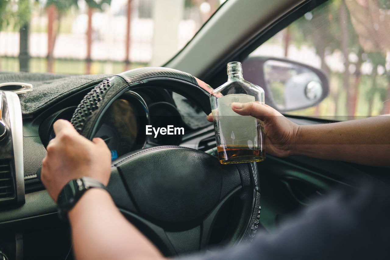 cropped hand of man holding coffee in car