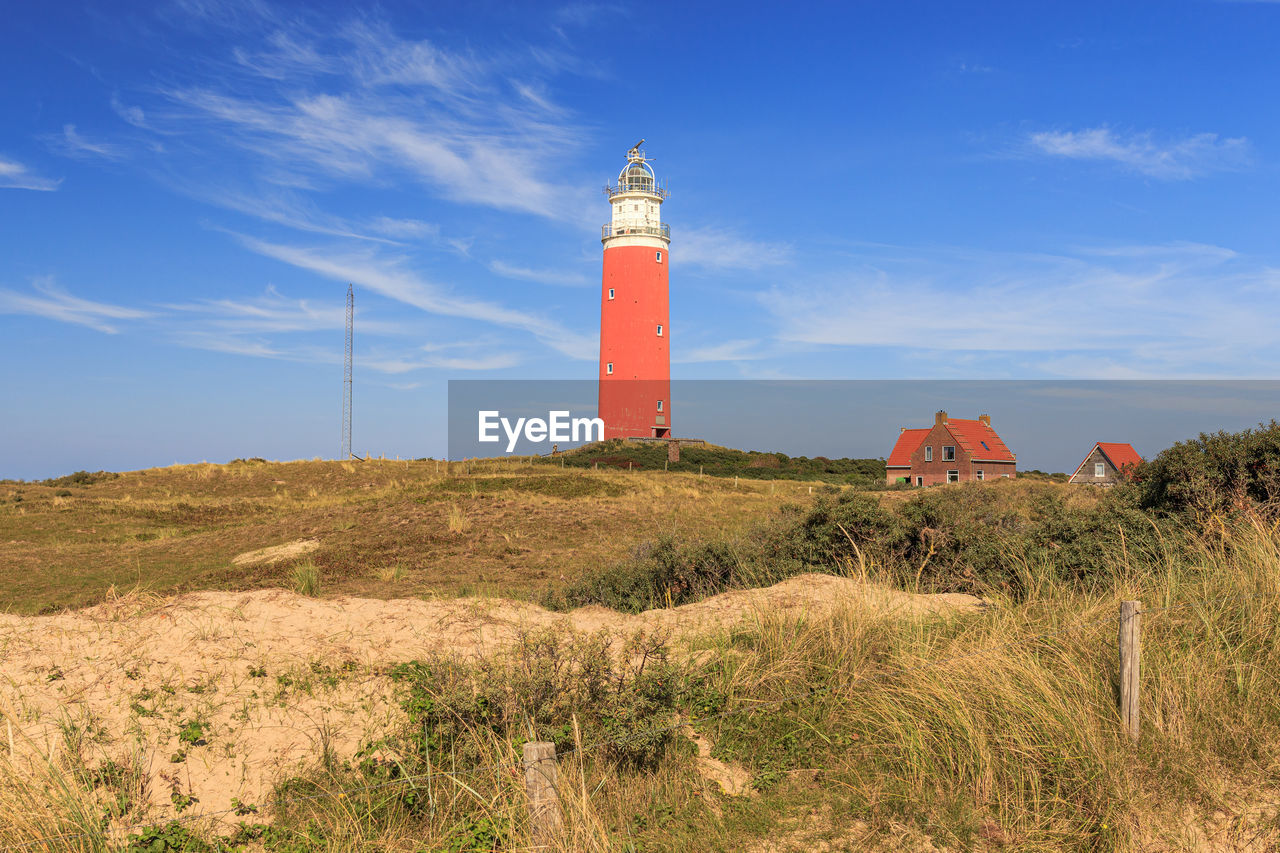 Lighthouse on field against sky