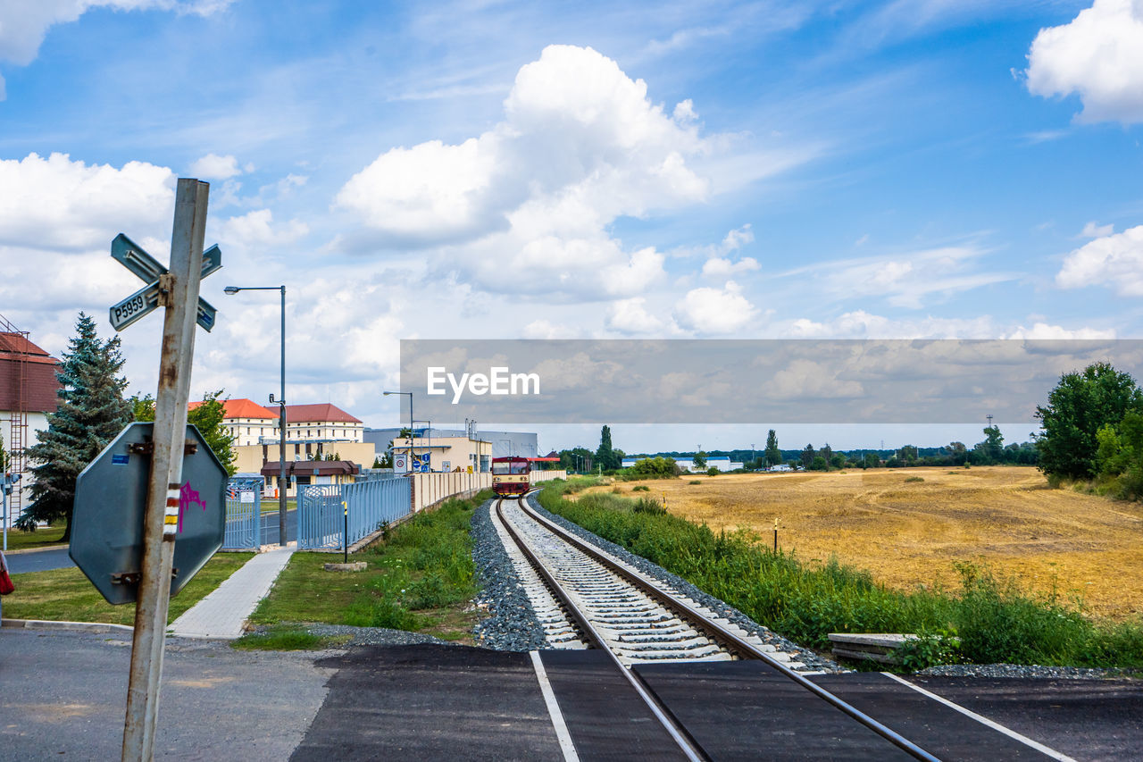 RAILROAD TRACKS ON FIELD AGAINST SKY