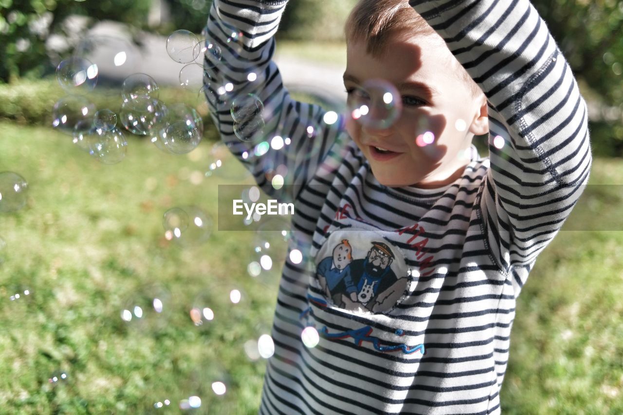 Boy playing with bubbles in park