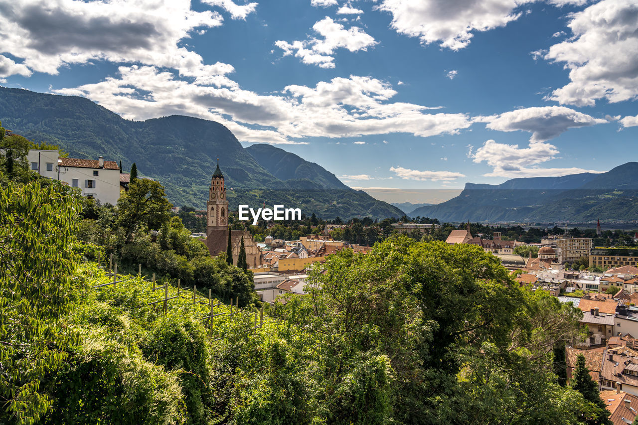 architecture, mountain, building, building exterior, built structure, city, sky, landscape, environment, mountain range, nature, plant, tree, scenics - nature, travel destinations, residential district, land, travel, cloud, house, beauty in nature, town, cityscape, tourism, no people, valley, outdoors, village, religion, high angle view, history, the past, rural area, rural scene, summer, day, blue, flower, sunlight, mansion