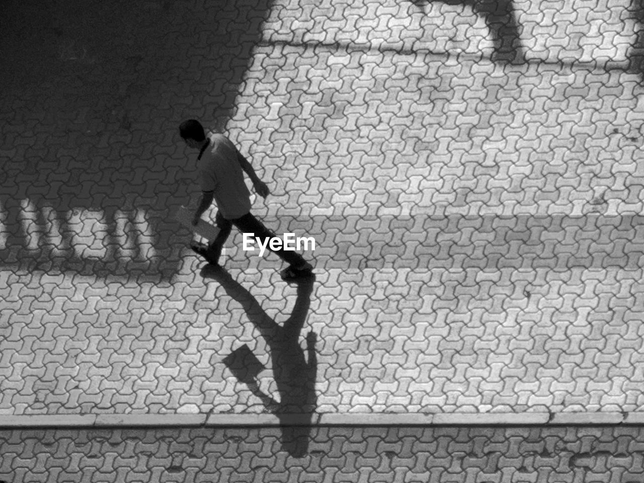 HIGH ANGLE VIEW OF MAN WALKING ON STREET IN CITY