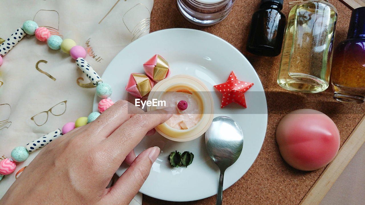 Composition of cosmetics products and skin care set with white dish,spoon and human hand.