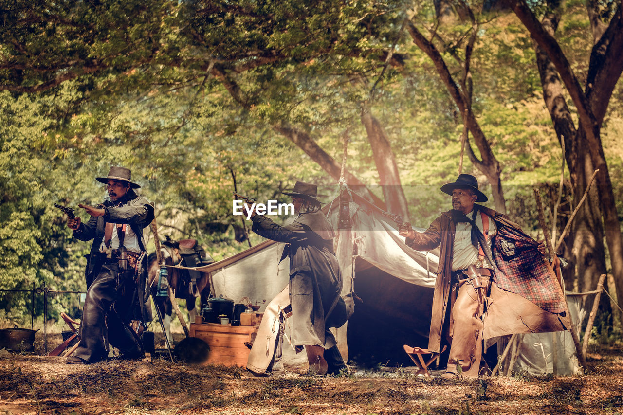 Men aiming guns in forest