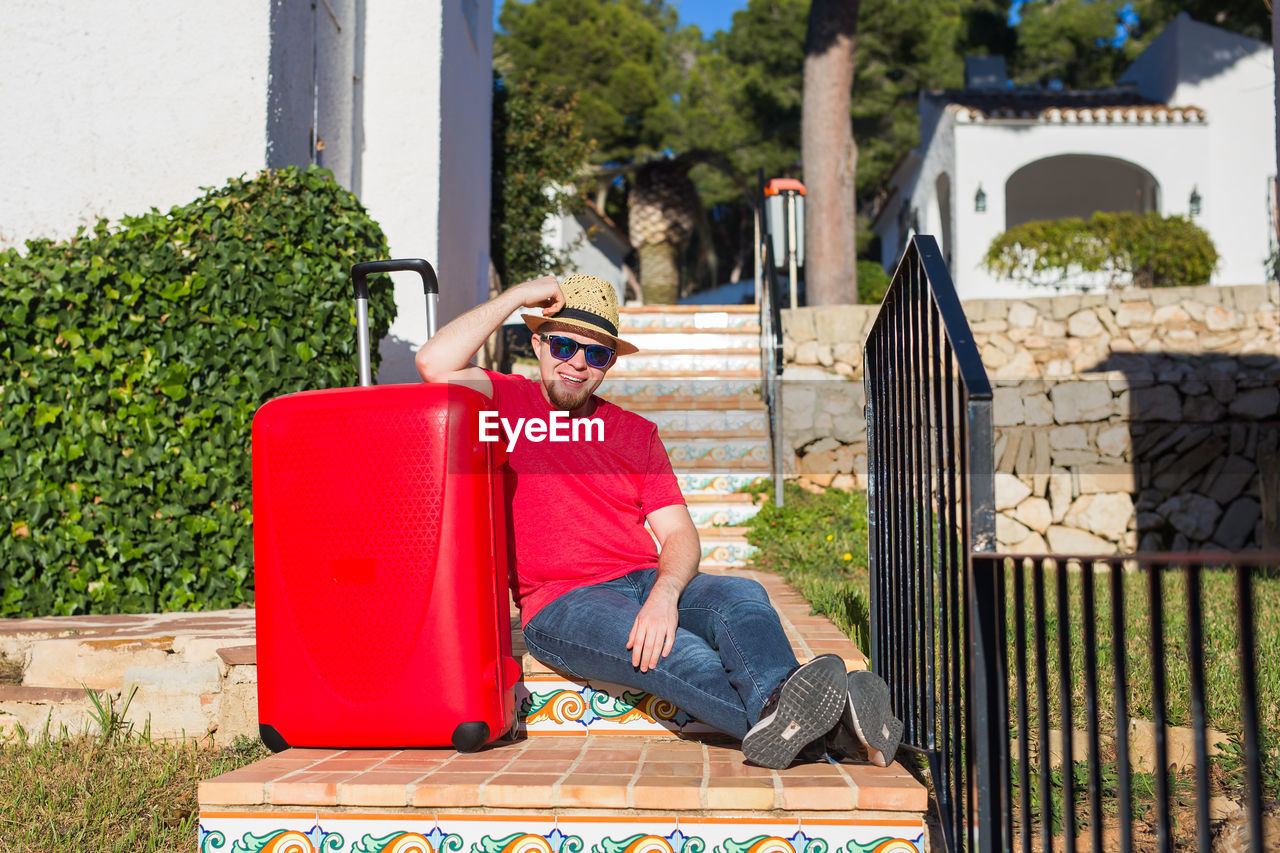 PORTRAIT OF MAN SITTING ON SUNGLASSES