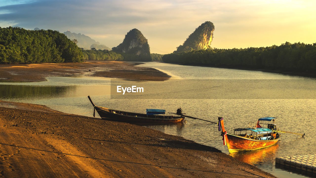 BOATS MOORED ON SHORE AGAINST SKY