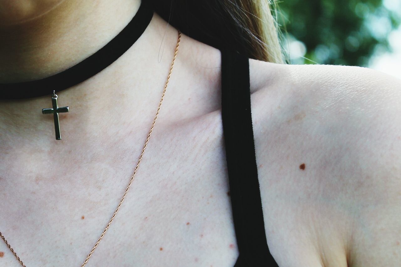 Midsection of woman wearing choker with cross pendant