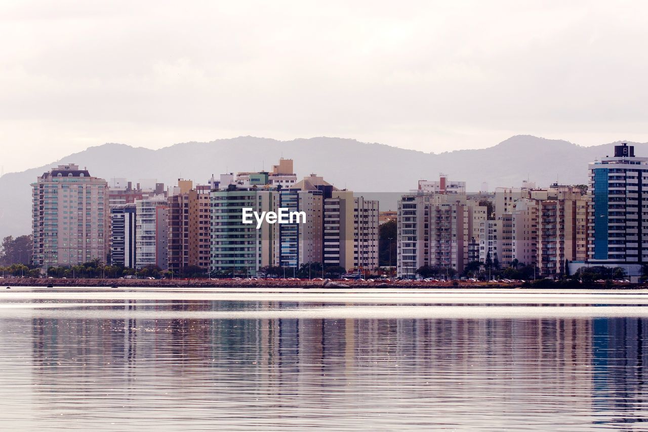 Reflection of buildings in lake against sky in city