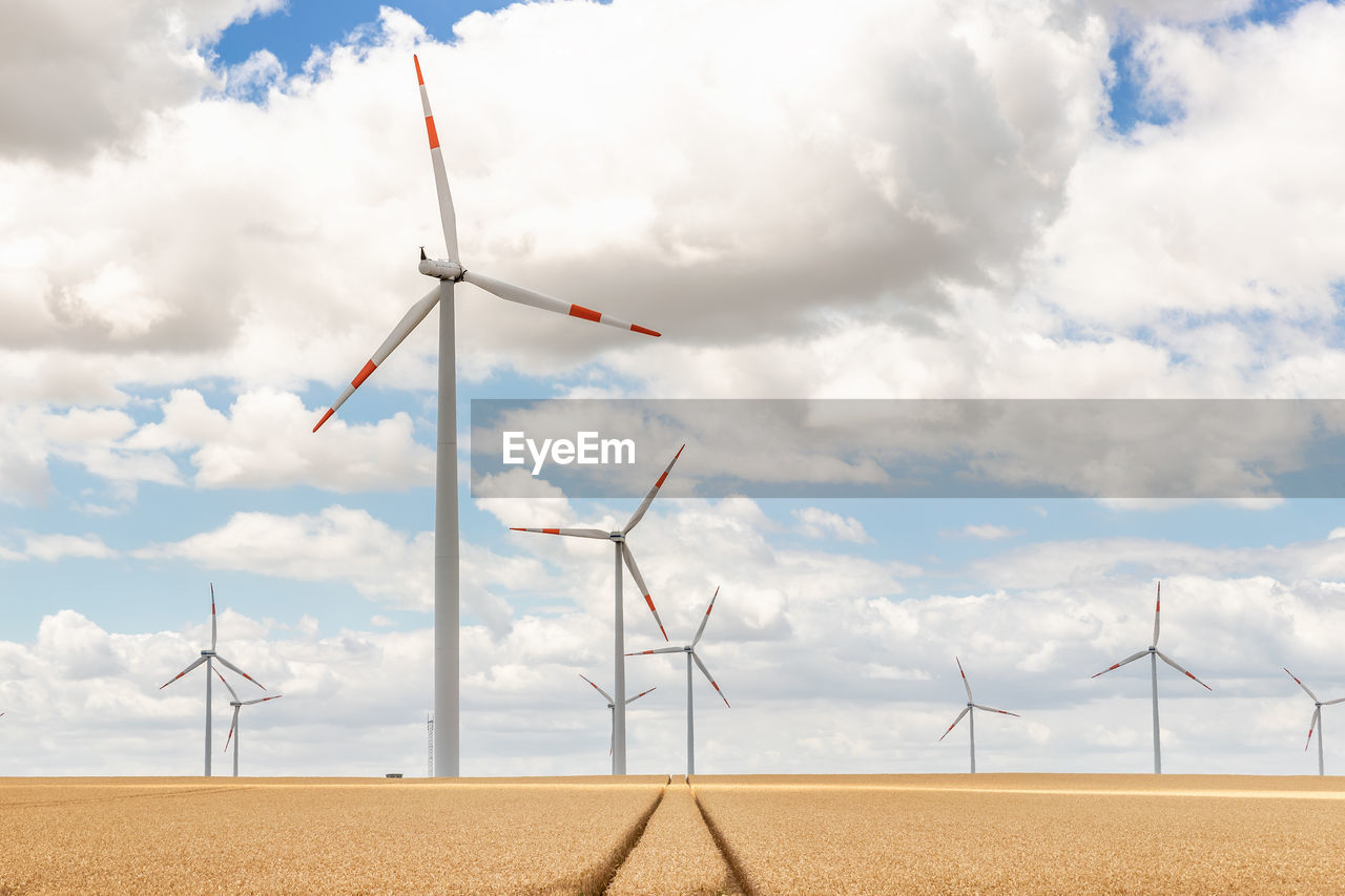 wind turbines on field against sky