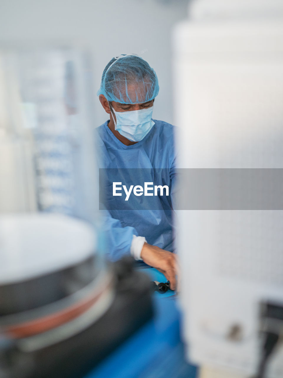 Mature man in medical uniform smiling and looking away while working in modern clinic