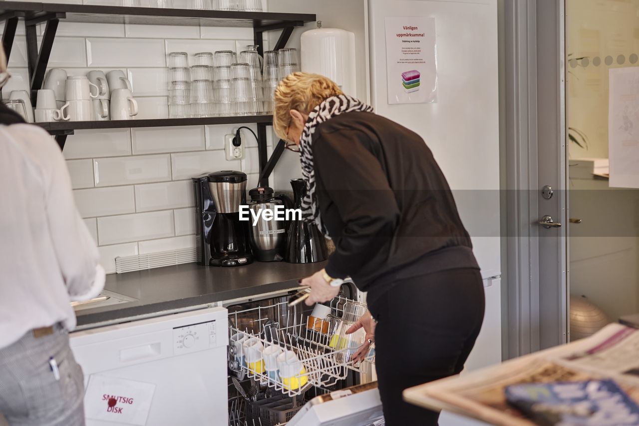 Woman putting dishes into dishwasher