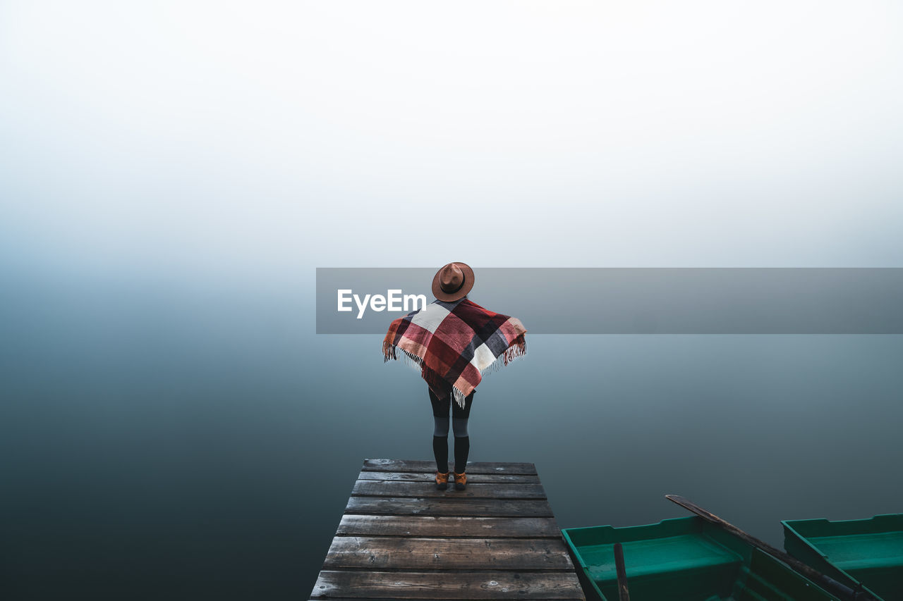 rear view of woman walking on pier over lake