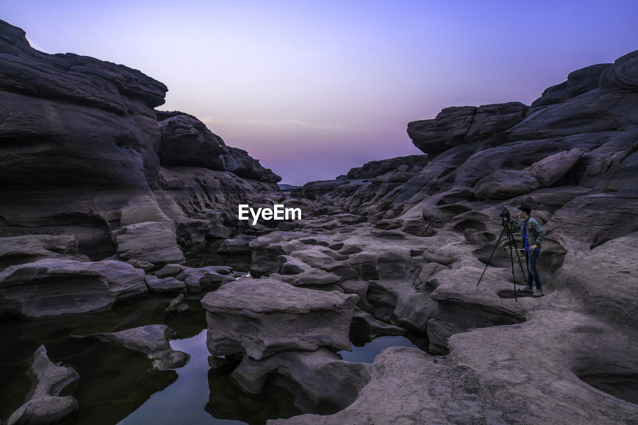 Man photographing of rock formations against sky