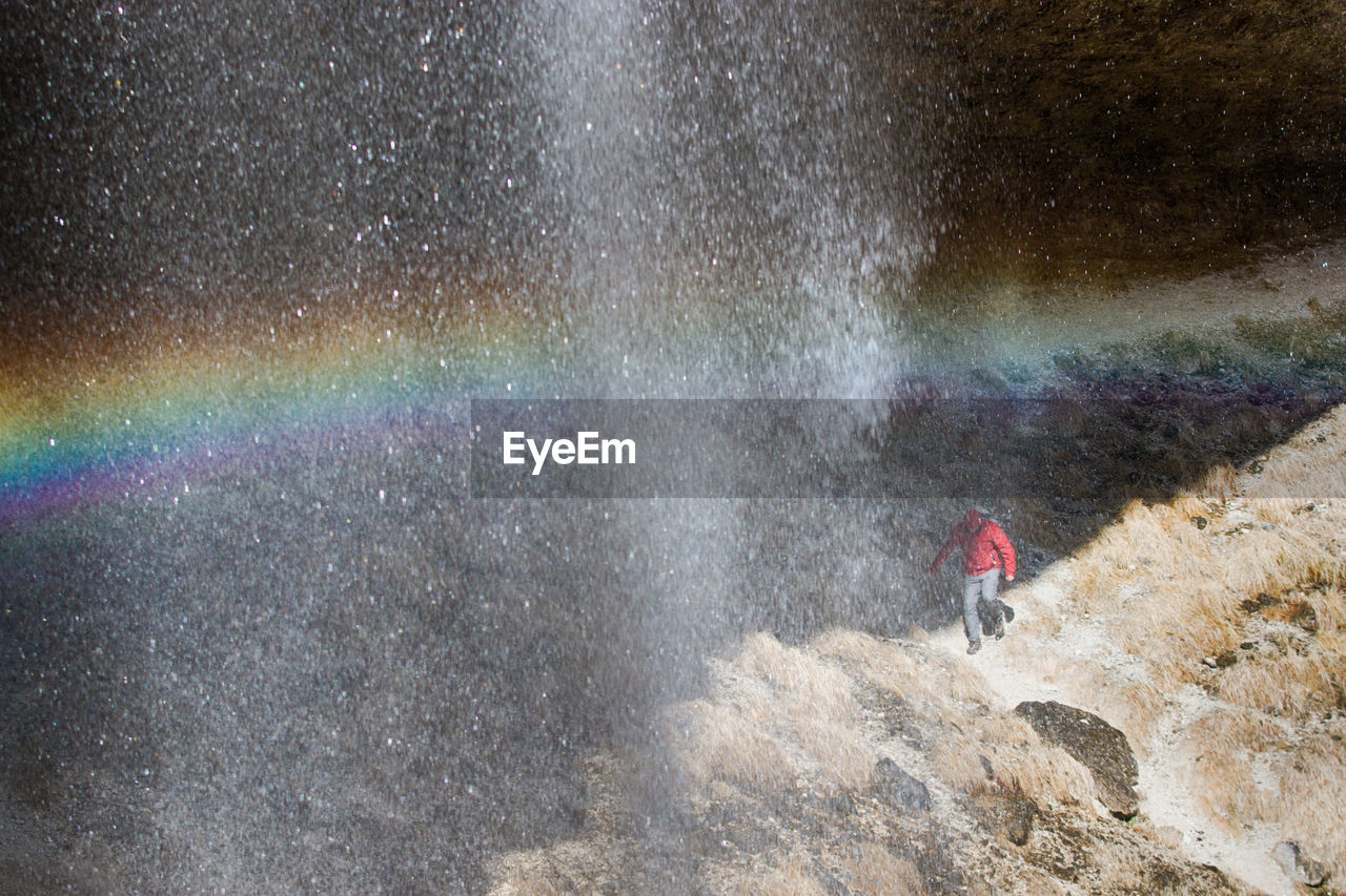 High angle view of woman walking on rock formation by waterfall