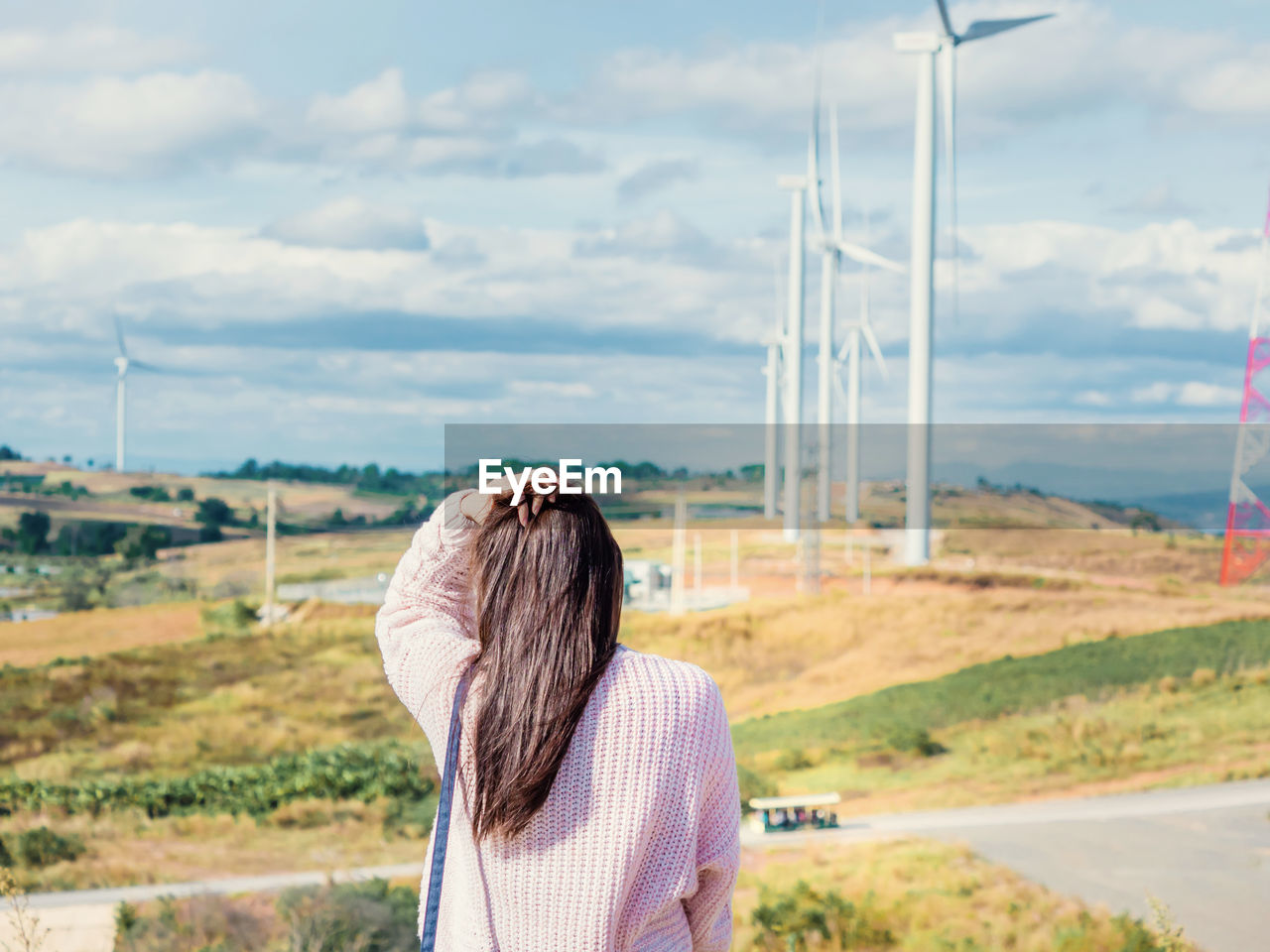 Rear view of woman standing against windmills on landscape