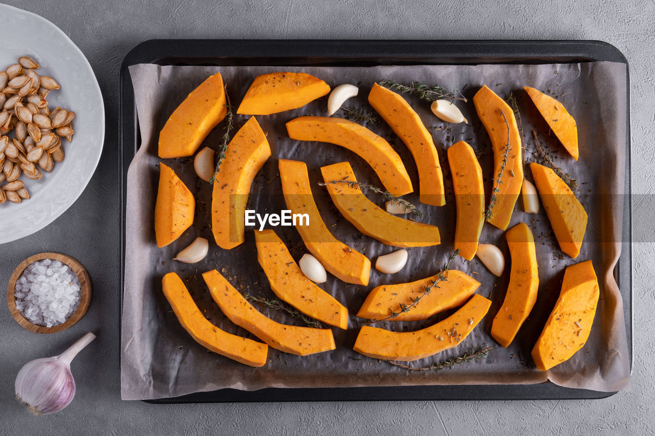 Pieces of  pumpkin prepared for baking. pumpkin on baking sheet with olive oil, garlic and dry thyme