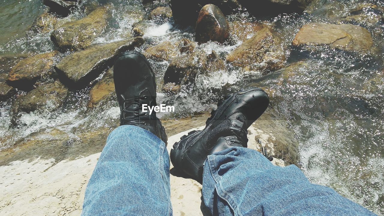 LOW SECTION OF MAN WITH WOMAN STANDING AGAINST WATER