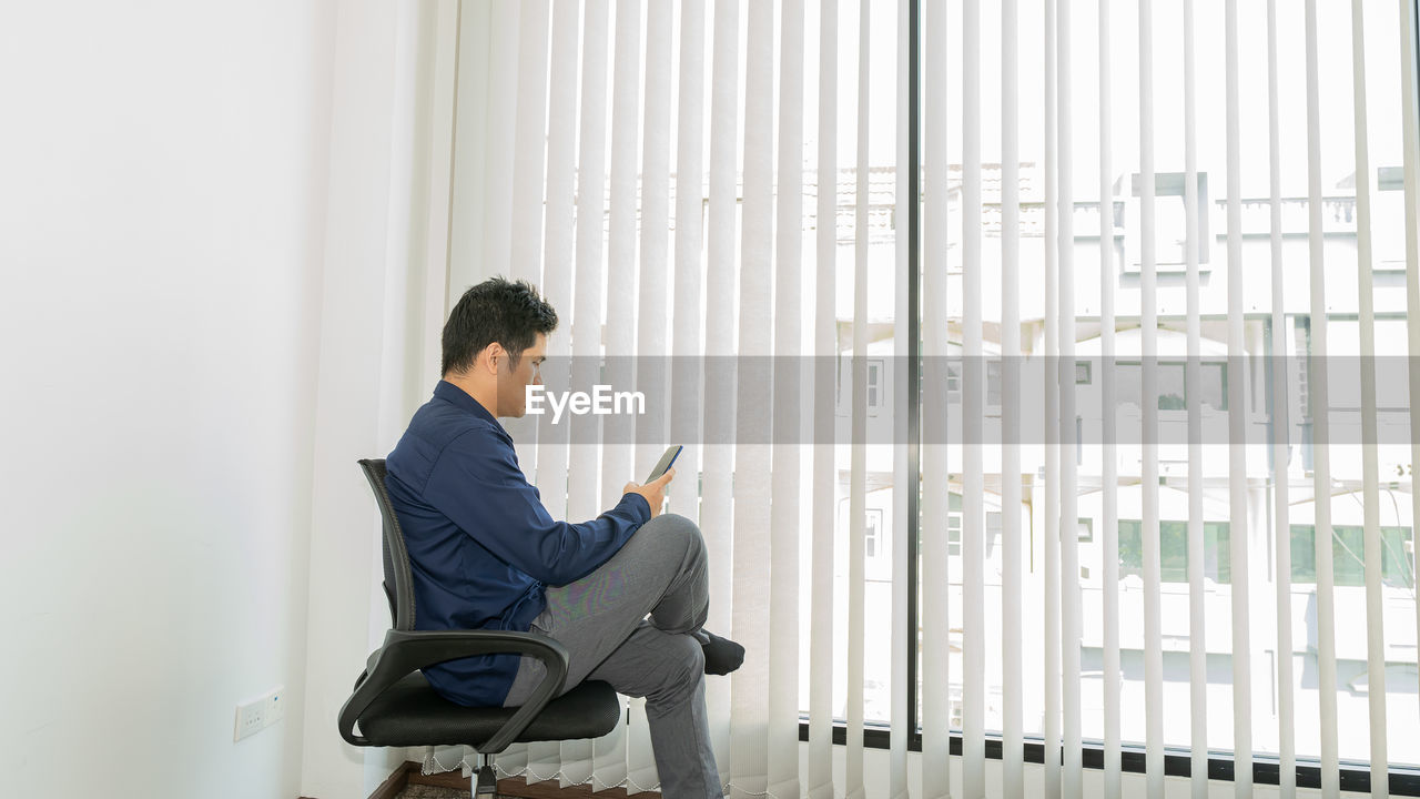 Side view of businessman using mobile phone in office