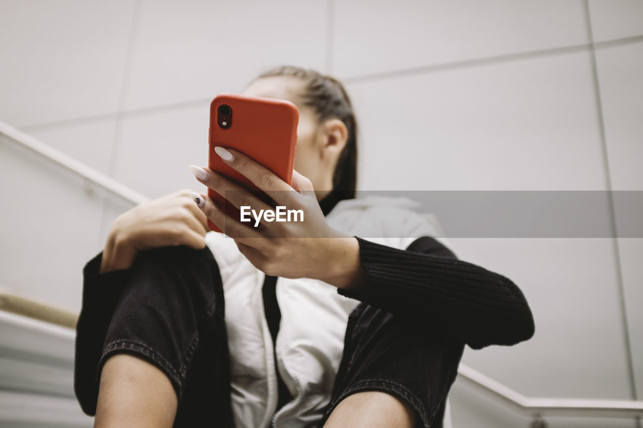 Young woman using phone while sitting on steps