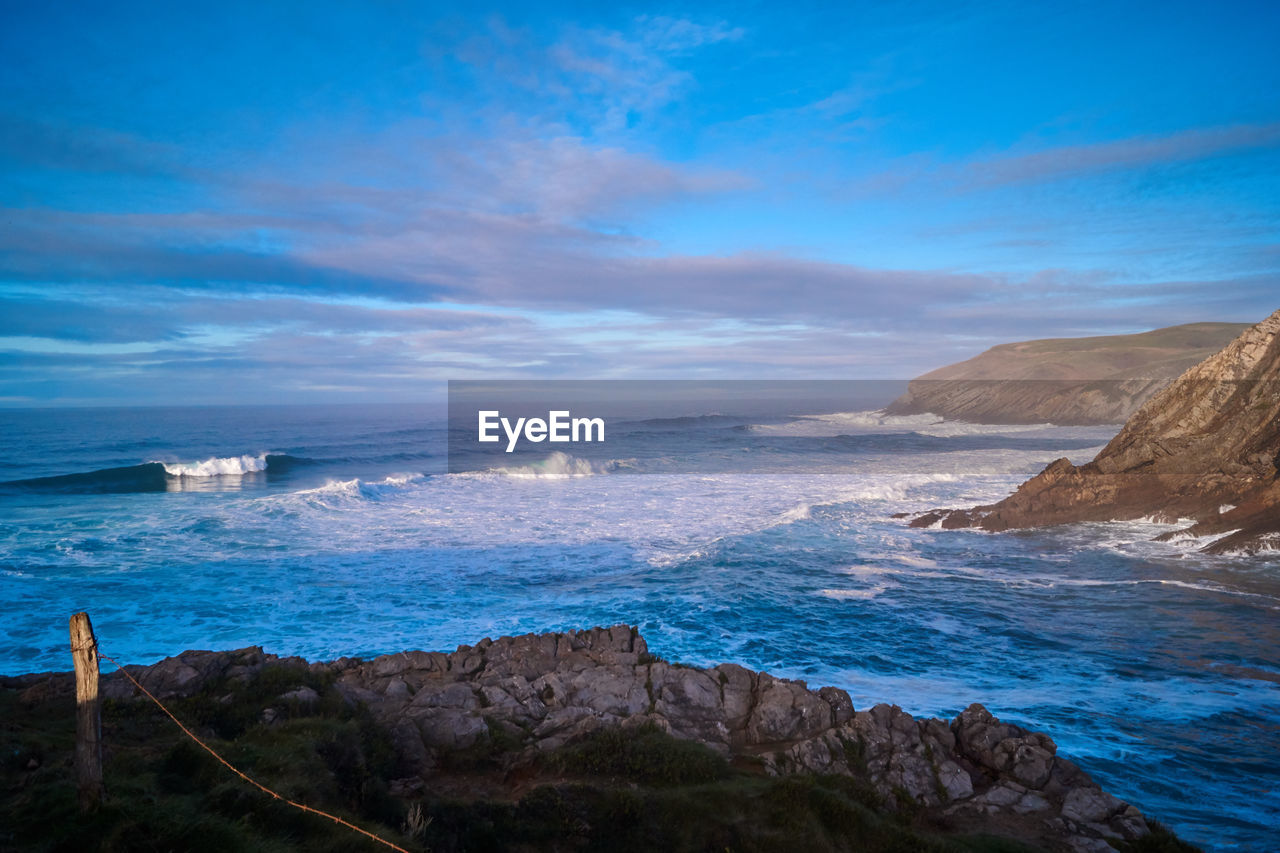 SCENIC VIEW OF ROCKY BEACH AGAINST SKY