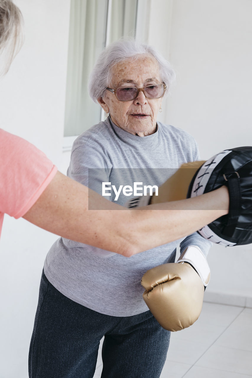 Senior woman boxing with fitness instructor