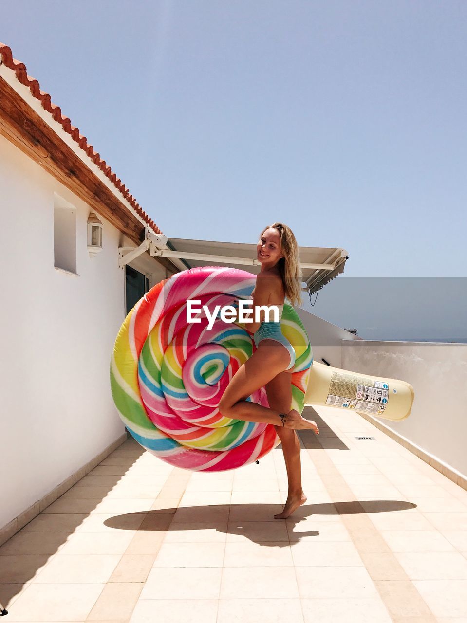 Woman with inflatable ring standing against sky