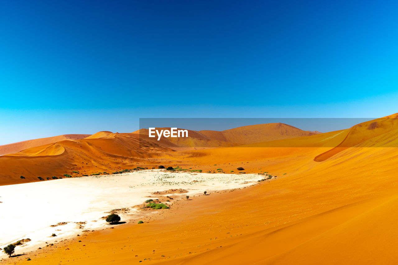 Scenic view of desert against clear blue sky