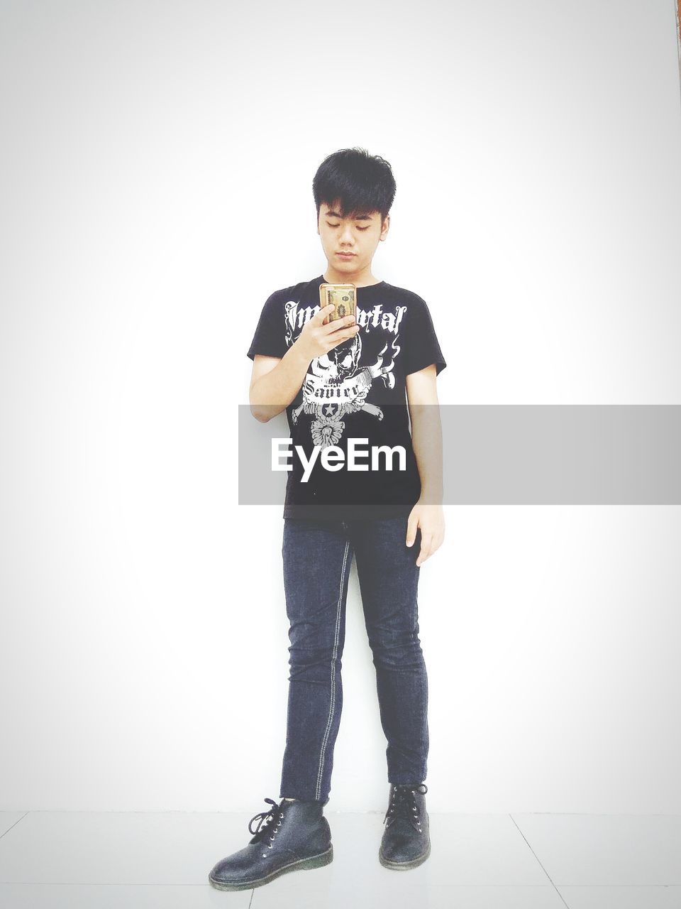 FULL LENGTH PORTRAIT OF SMILING BOY STANDING AGAINST WHITE BACKGROUND