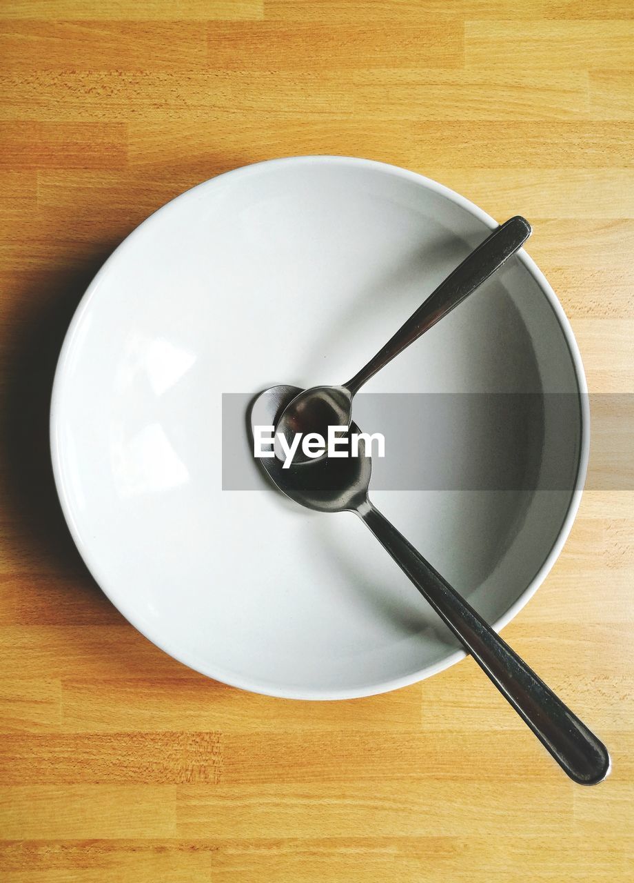 High angle view of spoons in empty bowl over table