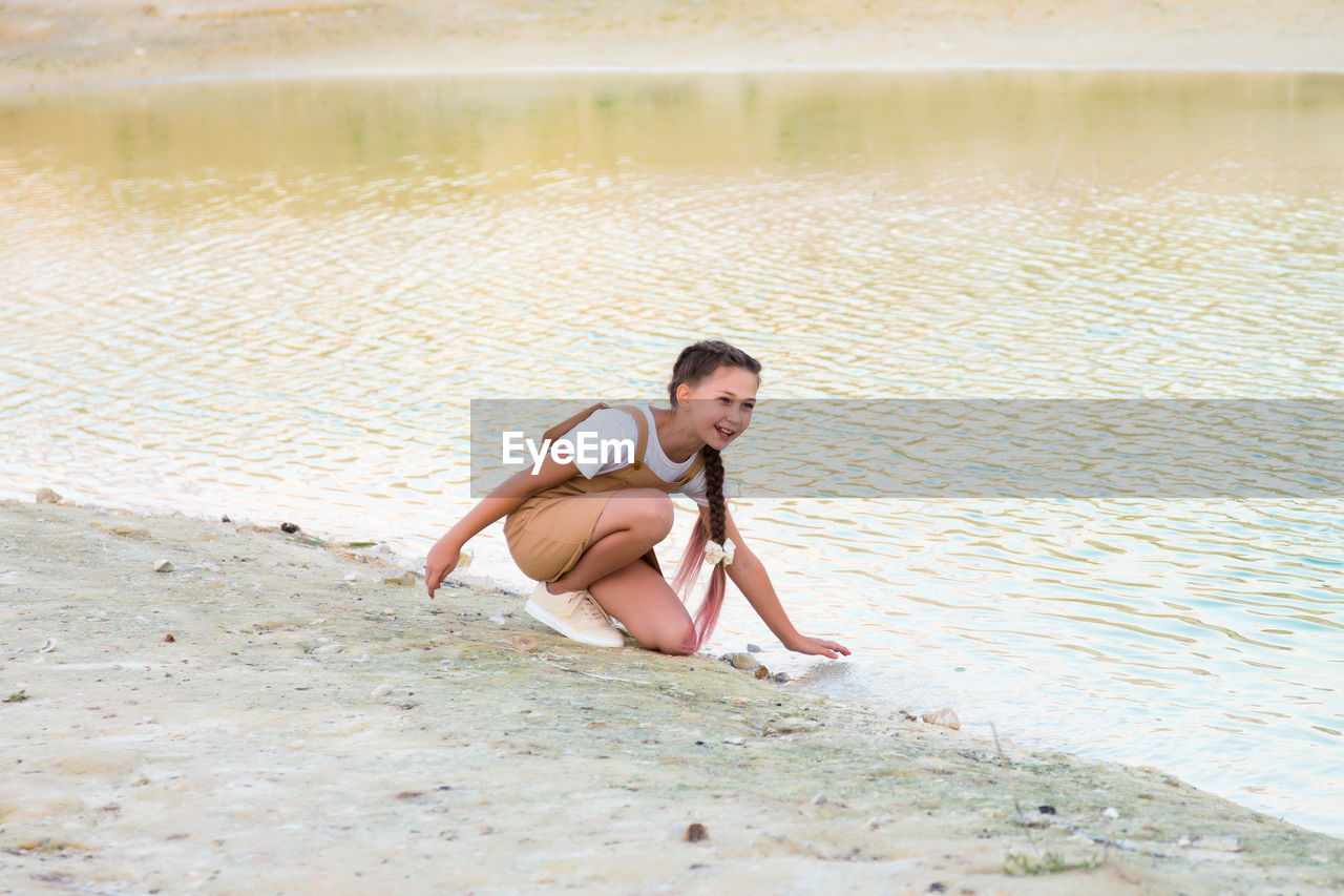 Teenage girl splashes water from river and laughs.